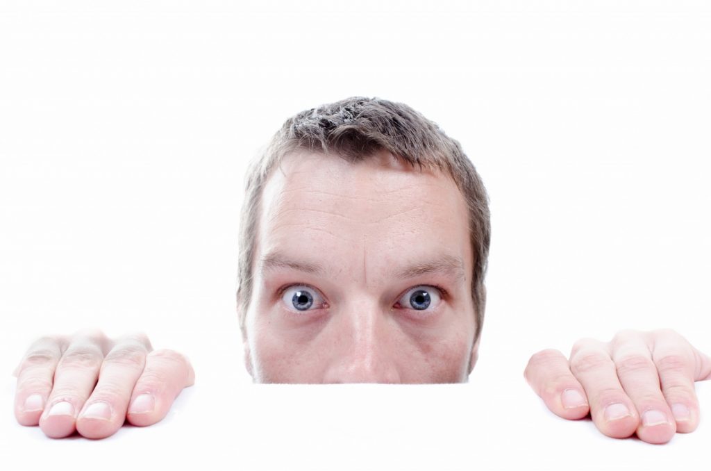 A man hiding from something scary - he has a phobia and would benefit from hypnotherapy