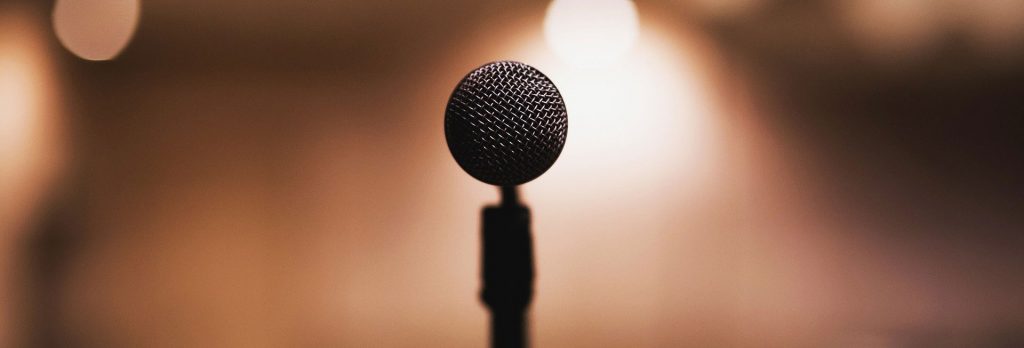 A single microphone on a stage symbolising a fear of public speaking, stage fright, anxiety, and making wedding speeches, by performers, the best man, actors, magicians, comedians, which could easily be treated by hypnotherapy in Wrexham and online